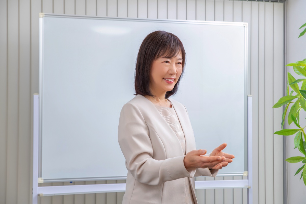ホワイトボードの前で説明する佐藤亮子